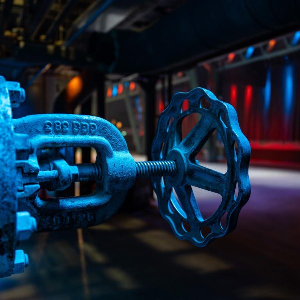 Nahaufnahme eines blauen Ventilrades in Neonlicht-Industrieumgebung